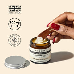 A jar of Kloris High Strength CBD Balm, with the lid off, showing the white balm inside. The label on the jar indicates it is a luxury CBD balm with 800mg CBD.