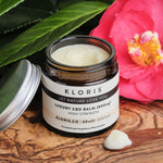 CBD balm on a wooden board with botanicals in the background