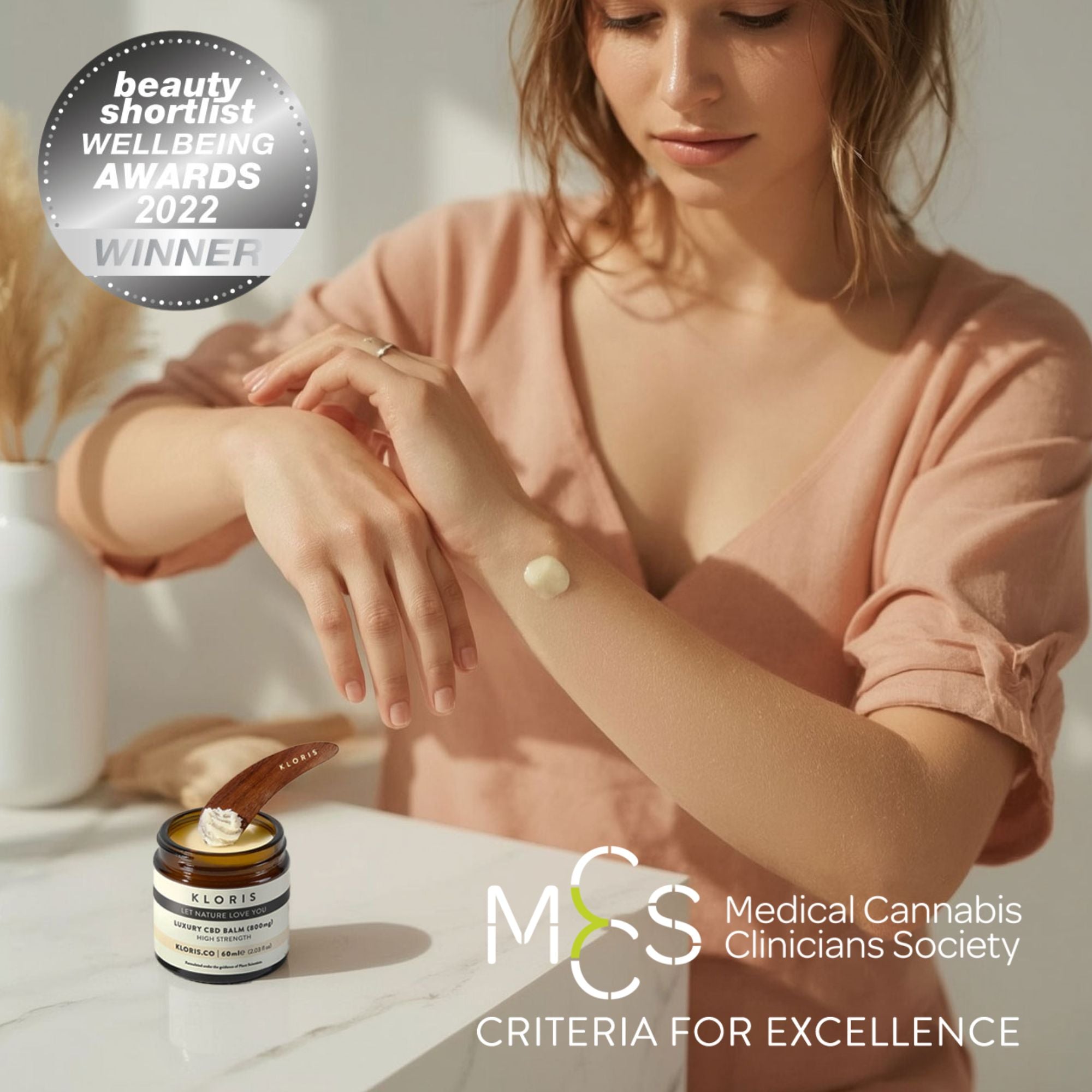 Woman applying CBD balm to her wrist with a jar of cream on a table, surrounded by text about awards.