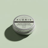 A round silver metal tin of Kloris Rapid Comfort Botanical Recovery Balm, set against a solid sage green background with a soft shadow.